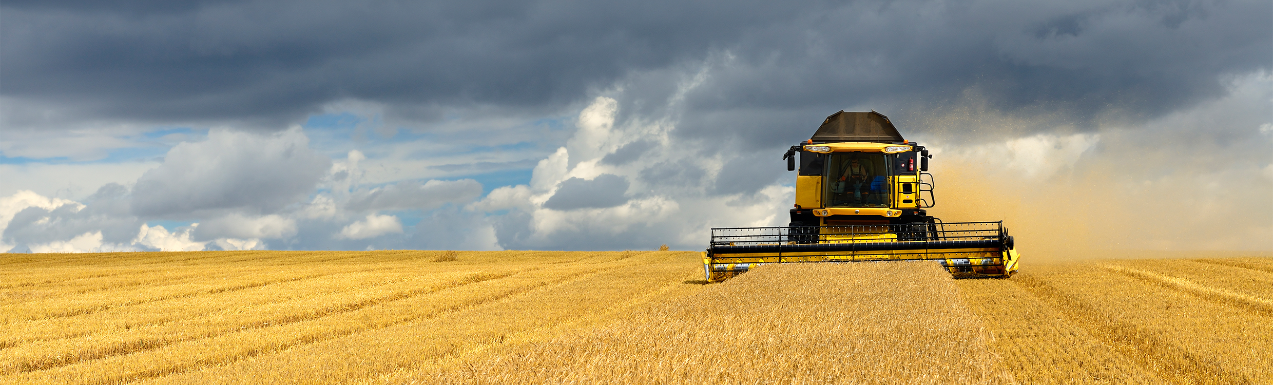 Tractor in a field with dark sky in the distance